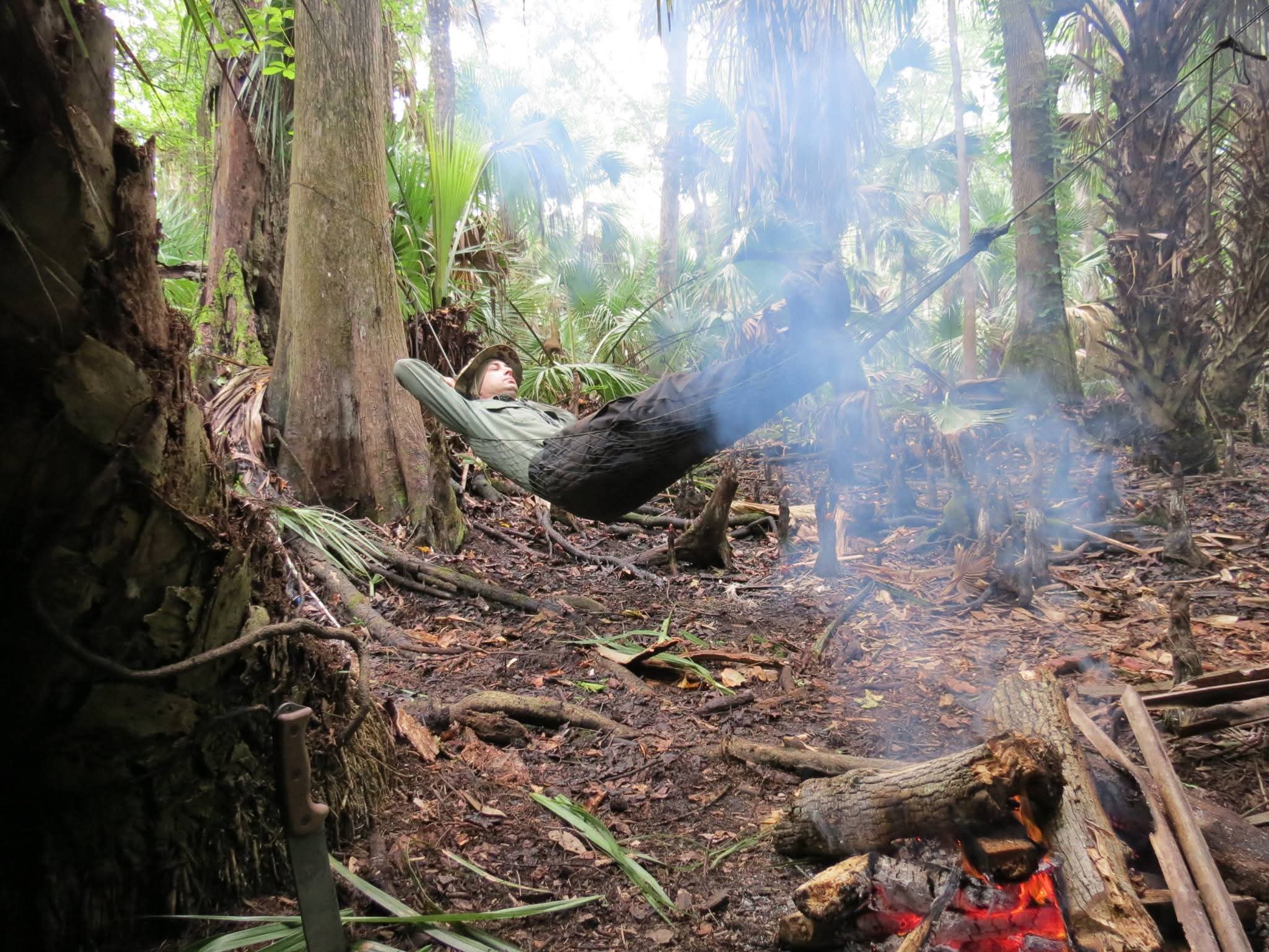 Doug Sahr relaxing in a hammock by a campfire in a Florida forest